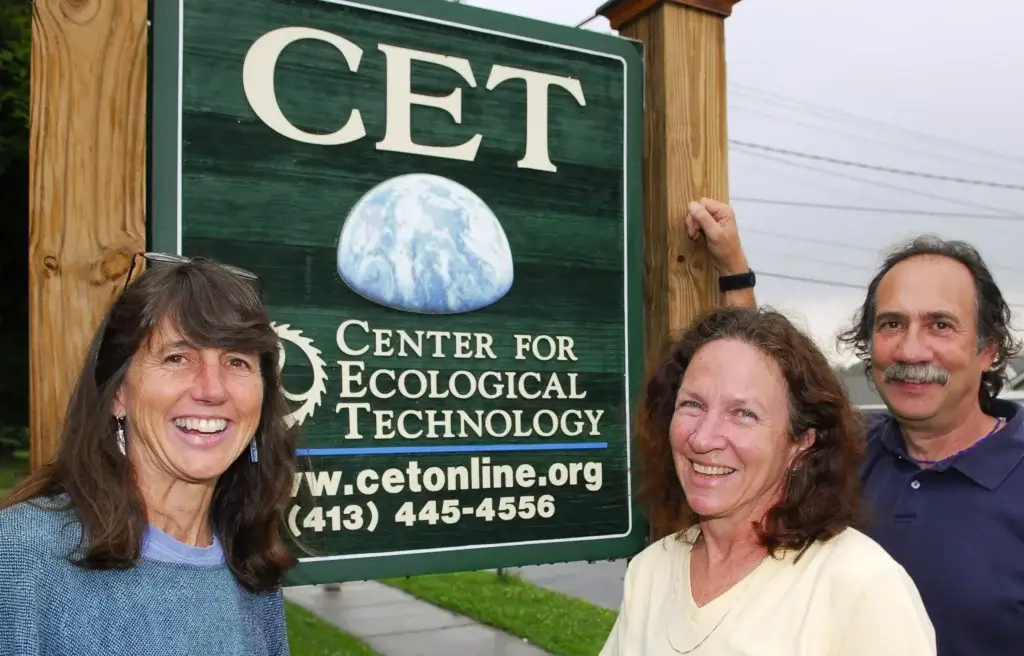 Directors01 Three people smiling next to a sign for CET, Center for Ecological Technology, outside the organization’s building.